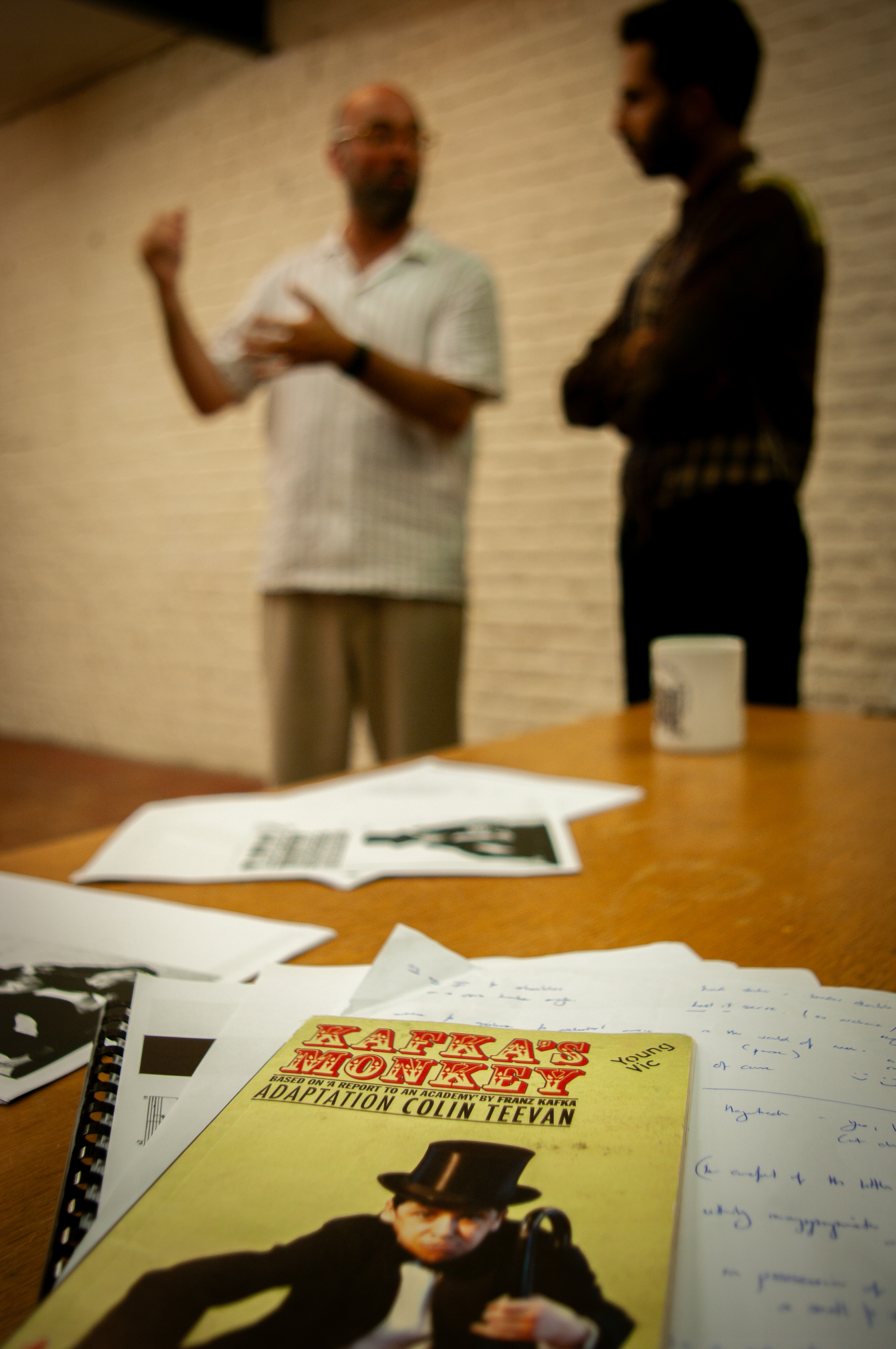 Rehearsal scripts on a table with conversation behind