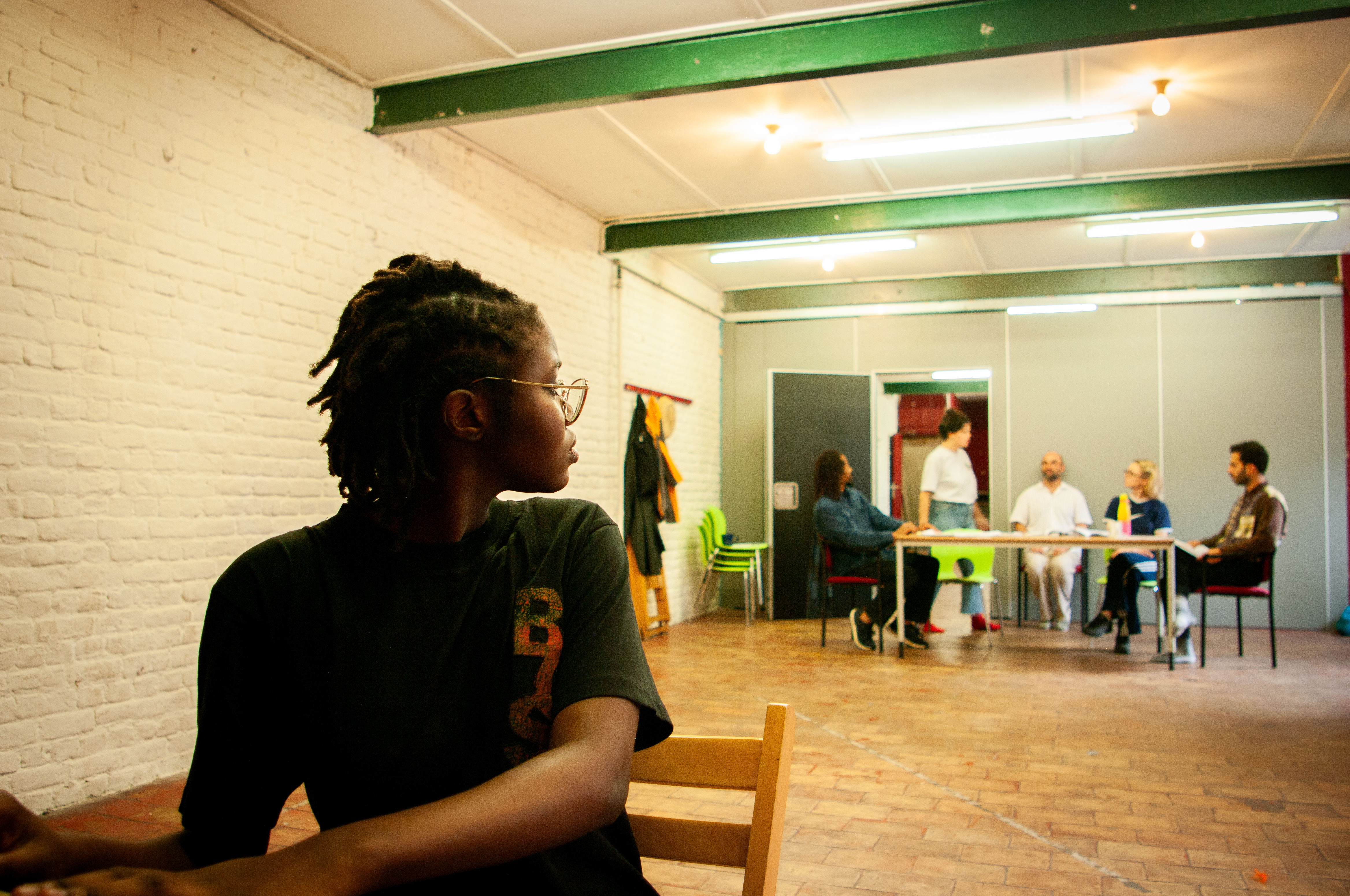 Seated participant watching the rehearsal across the room